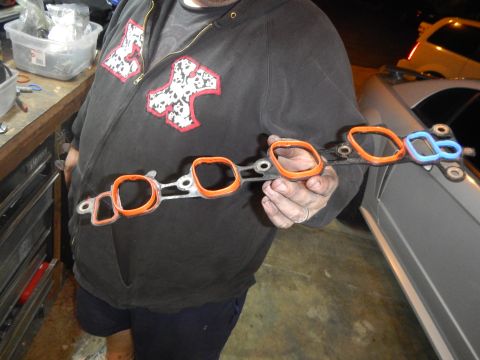 2002 Ford Mustang - A person holds an intake manifold gasket set with orange and blue seals.