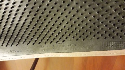 1995 Ford Bronco - Close-up of a rubber floor mat's underside, revealing its textured surface and embossed markings.