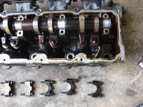 1994 Ford Bronco - Disassembled engine cylinder head with camshaft and rocker arms, with separate rocker arm assemblies laid out.