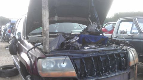 1994 Ford Bronco - Jeep Grand Cherokee engine bay with transmission removal in progress, with another vehicle visible.