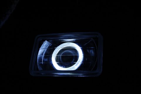 1985 Mercury Grand Marquis - Close-up of a vehicle headlight a bright halo ring, likely an aftermarket modification.