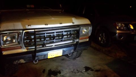 1979 Ford Bronco front end with grille guard and yellow license plate. Another SUV is parked to the right