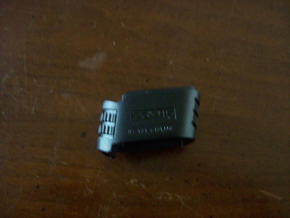 Black plastic part with ridges on one end and embossed text on the side