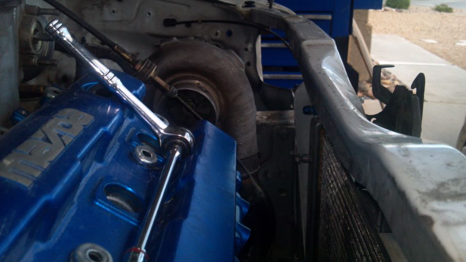 Close-up of a turbocharger and blue engine cover with a wrench on it