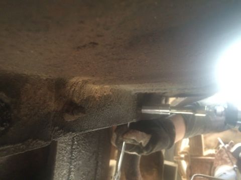 1979 Ford Bronco - Working on the undercarriage of a vehicle, likely removing a part.