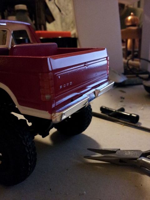 1995 Ford Bronco - Close-up view of the rear of a red pickup truck, showing the tailgate and chrome bumper with 'FORD' branding.