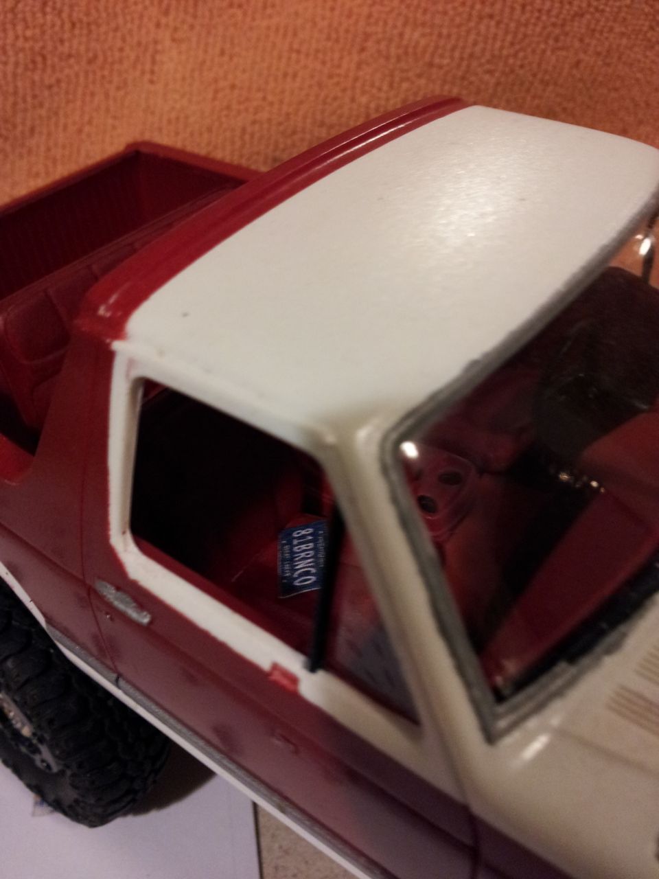 Red and white model car with a blue license plate reading '8 BRONCO' visible through the window