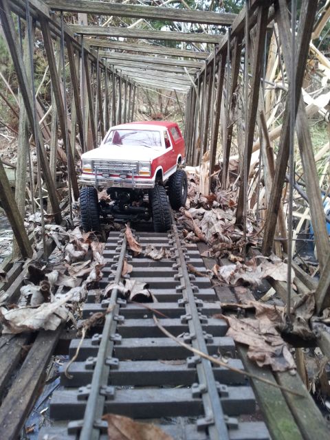 1995 Ford Bronco - RC 1995 Ford Bronco model navigating a weathered wooden bridge over model train tracks.