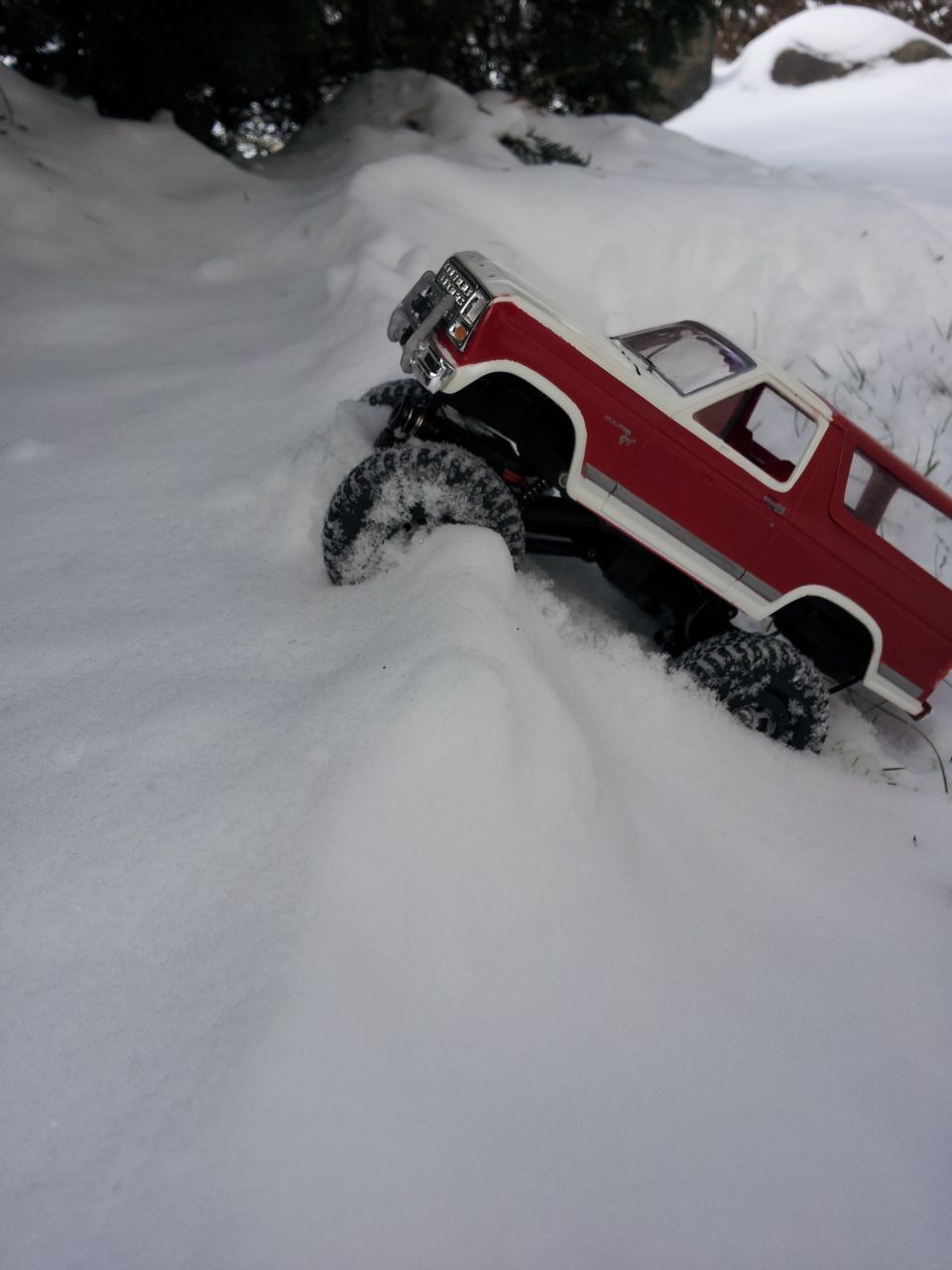 Red and white remote control truck driving through snow