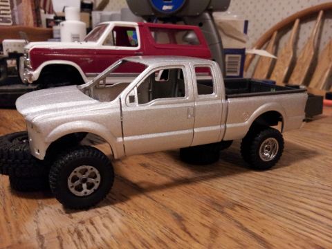 1995 Ford Bronco - A silver pickup truck model is shown with a red and white SUV in the background.