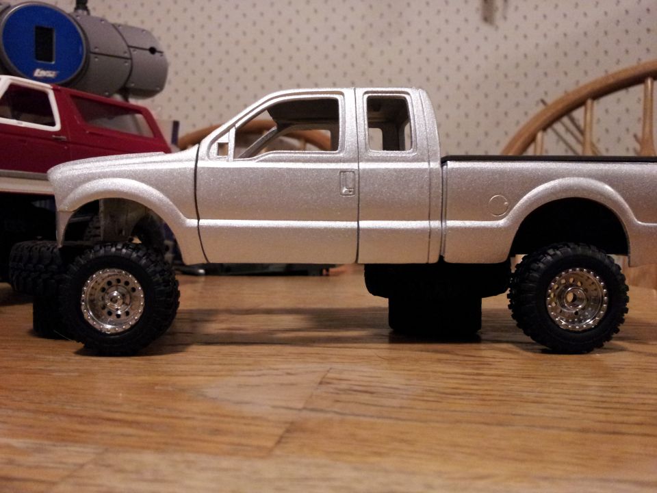 model pickup truck with large tires, another red model truck behind it