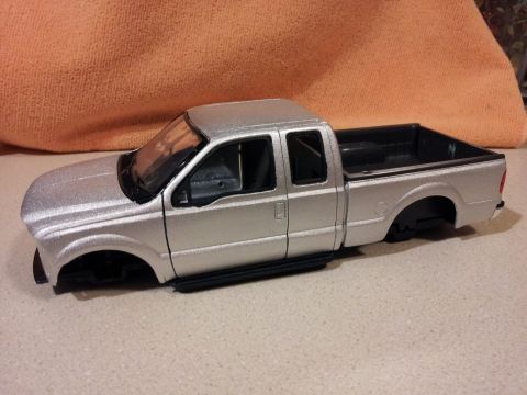 1995 Ford Bronco - Model pickup truck missing wheels sits on a flat surface with an orange cloth in the background.
