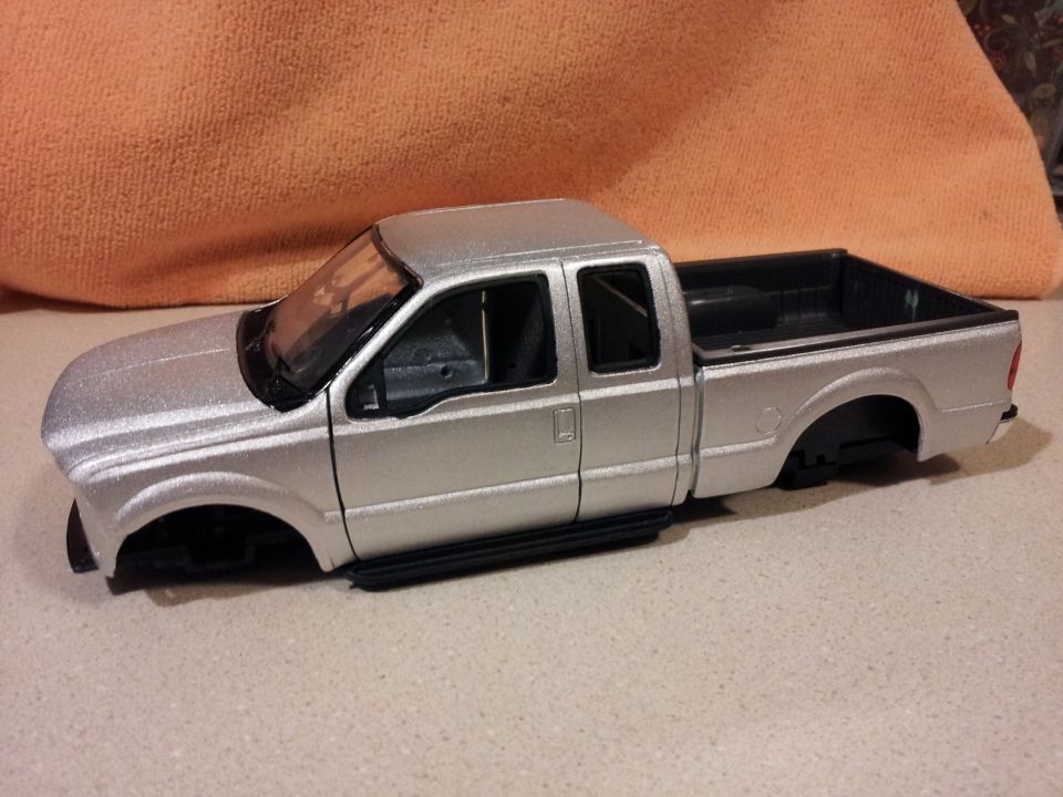 Silver pickup truck model with no wheels, showing the cab and bed