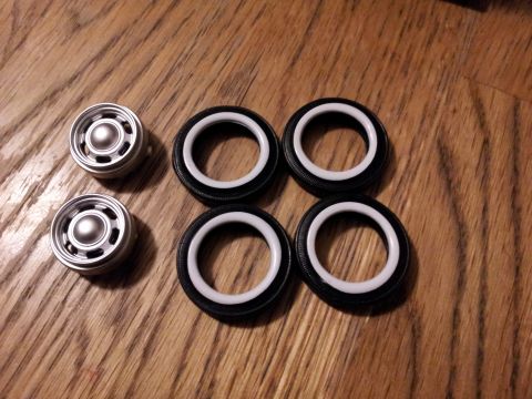 1995 Ford Bronco - Model car wheels and tires are laid out on a wooden surface, ready for assembly.