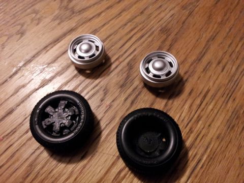 1995 Ford Bronco - Model car wheels and tires are displayed on a wooden surface.