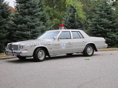 1991 Ford Crown Victoria - A vintage Rhode Island State Police car is parked on asphalt with trees in the background.