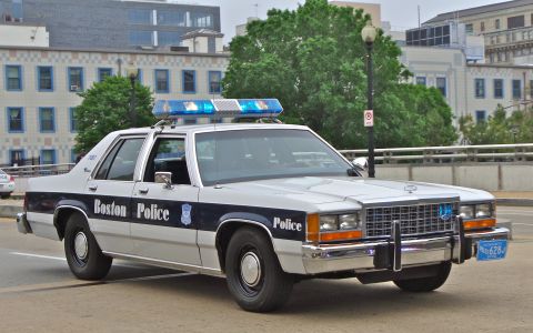 1991 Ford LTD Crown Victoria - White-and-blue Ford LTD Crown Victoria police sedan lettered 'Boston Police' with a department badge decal, shown from a low 3/4 front angl…