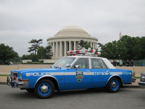 1991 Ford LTD Crown Victoria - A vintage police car is parked with a prominent domed building in the background.