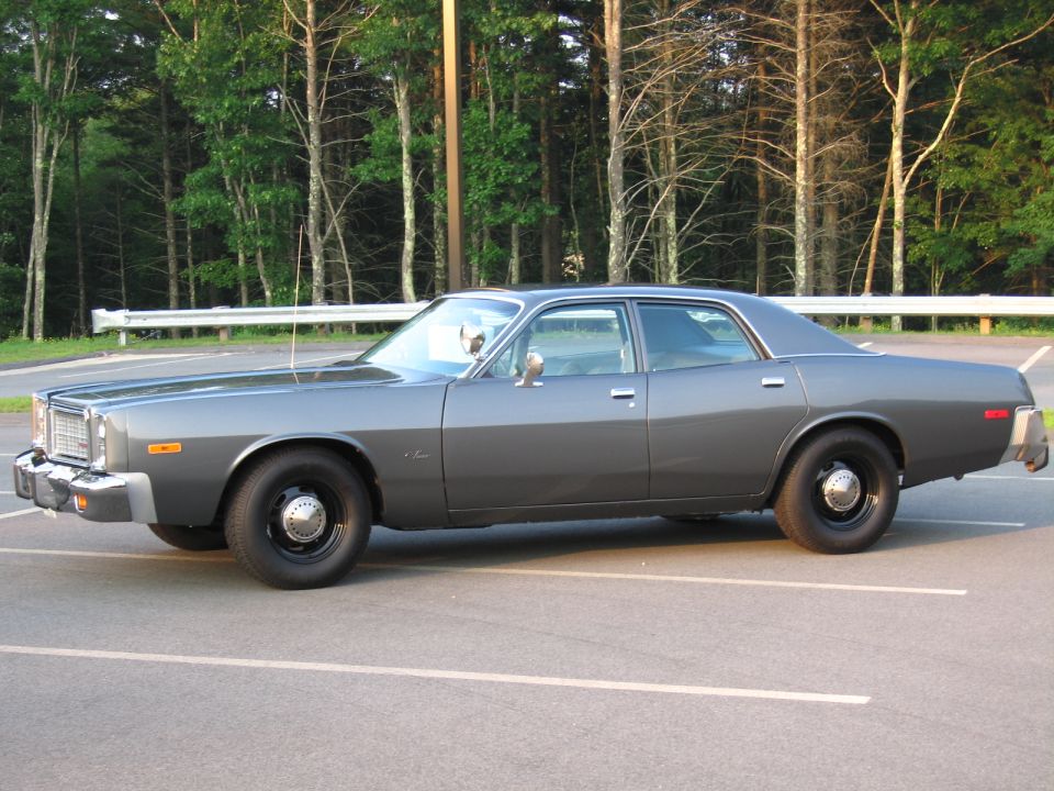 Gray 1970s Dodge four-door sedan, side view, steel wheels and spotlight, parking lot