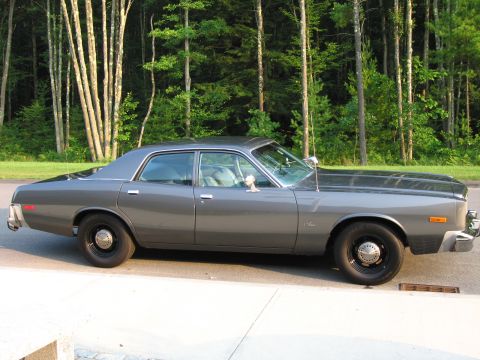1991 Ford LTD Crown Victoria - A gray sedan is parked on the side of the road with a wooded area behind it.