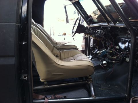 1995 Ford Bronco - The interior of a vehicle shows racing seats and a roll cage, with the dashboard disassembled.