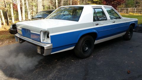 1991 Ford LTD Crown Victoria - 3/4 rear view of a Ford LTD Crown Victoria sedan mid-restoration in fresh blue-and-white two-tone police paint, sitting in a paved driveway…