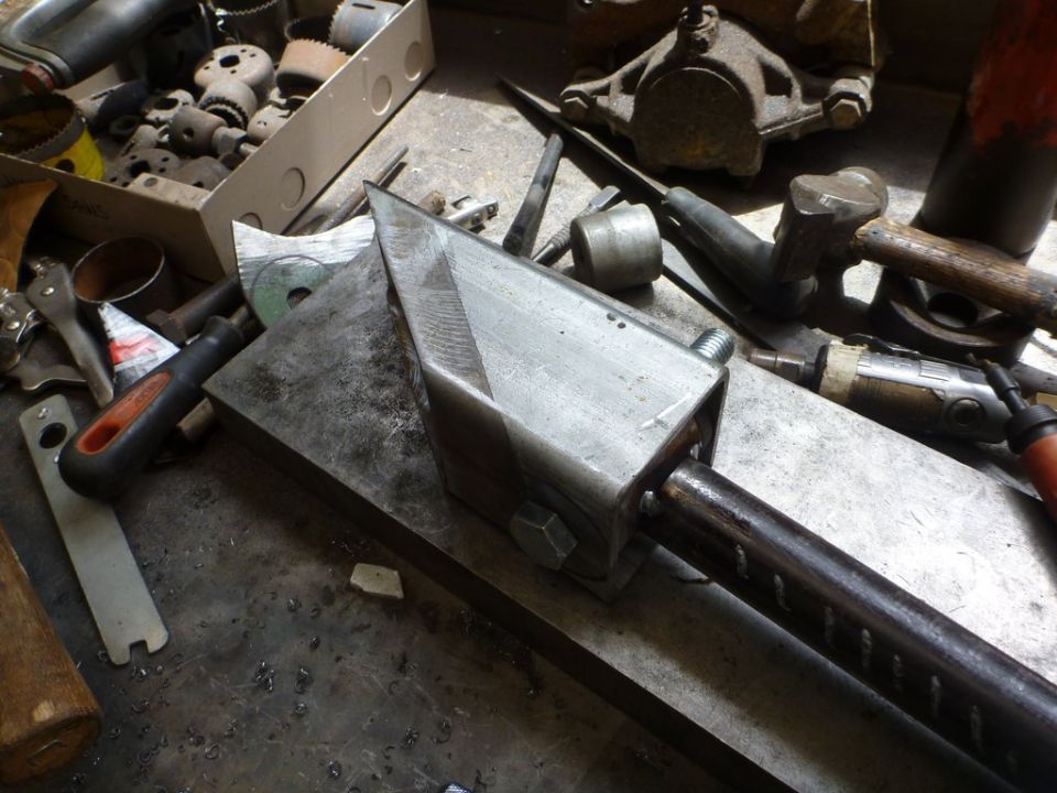 Custom suspension part with bolts and metal tubing on a workbench