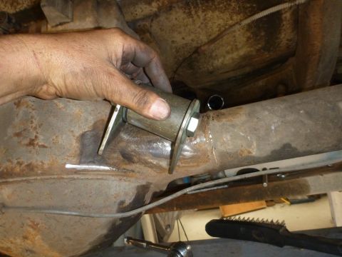 1964 Mercury Monterey - A mechanic's hand is shown installing a new suspension bushing onto a vehicle's axle. The surrounding metal shows signs of rust.