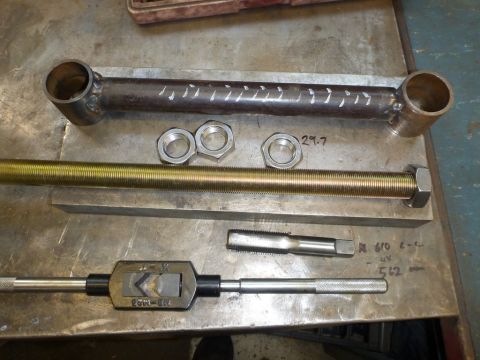 1964 Mercury Monterey - A suspension component, nuts, a threaded rod, and a tap wrench are laid out on a metal workbench.