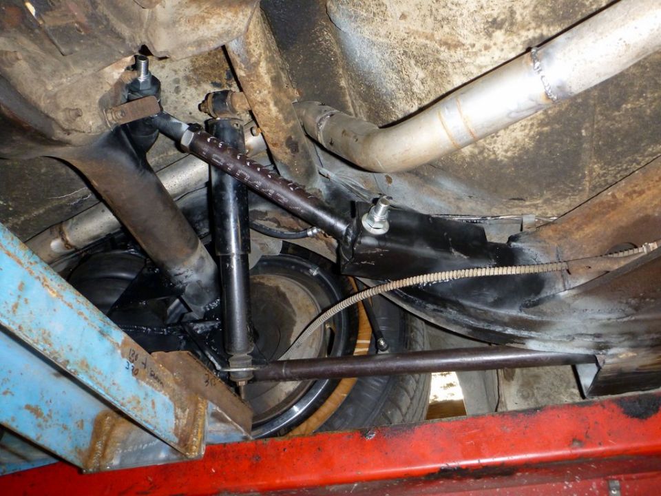 Underside view of a car's rear suspension with shocks, springs, and exhaust pipe