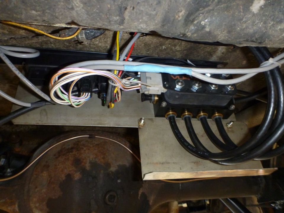 Air suspension manifold with wires and hoses attached to a vehicle's undercarriage