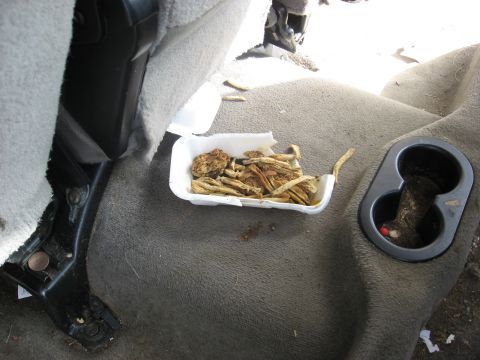 1994 Ford Bronco - Fast food leftovers and trash are visible on the passenger seat and in the cup holder of a vehicle's interior.