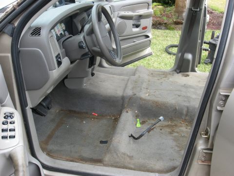 1994 Ford Bronco - The interior of a Dodge Ram 1500 shows a dirty floor and dashboard, with the driver's door ajar.