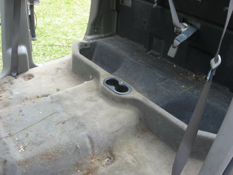 1994 Ford Bronco - The interior rear cargo area shows cup holders and seat belts, with grass visible outside.