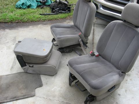 1994 Ford Bronco - Vehicle seats and center console removed from a vehicle, placed on a concrete surface.