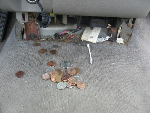 1994 Ford Bronco - Coins and a q-tip litter the carpeted floor of a vehicle's interior.