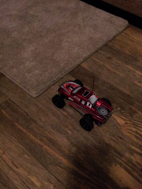 1995 Ford Bronco - A remote control monster truck sits on a wooden floor near a rug.