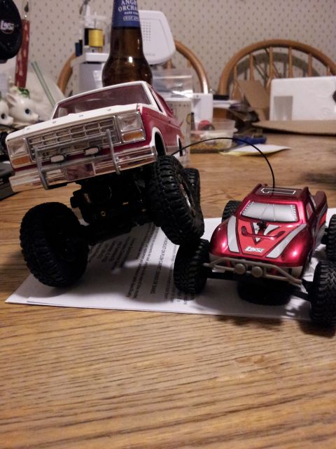1995 Ford Bronco - Two toy vehicles, a Ford Bronco and a truck, are positioned on a table, with one on top of a piece of paper.