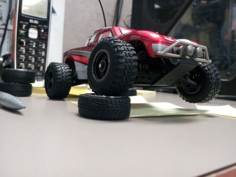 1995 Ford Bronco - A remote control monster truck is positioned on a desk with spare tires nearby.
