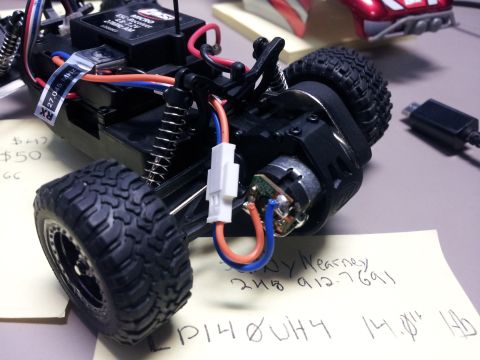 1995 Ford Bronco - Close-up view of a remote control car chassis, showing the motor, wiring, and suspension components.