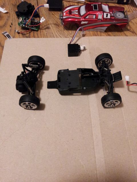 1995 Ford Bronco - Disassembled parts of a remote control truck, including the body, chassis, and electronic components, are laid out on a surface.