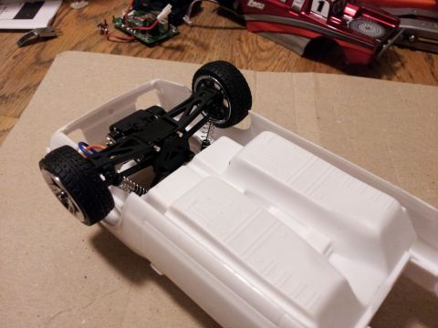 1995 Ford Bronco - The chassis of a white model car is shown, with its suspension and wheels attached.