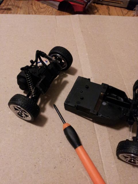 1995 Ford Bronco - Disassembled remote control car chassis and parts, with a screwdriver nearby.