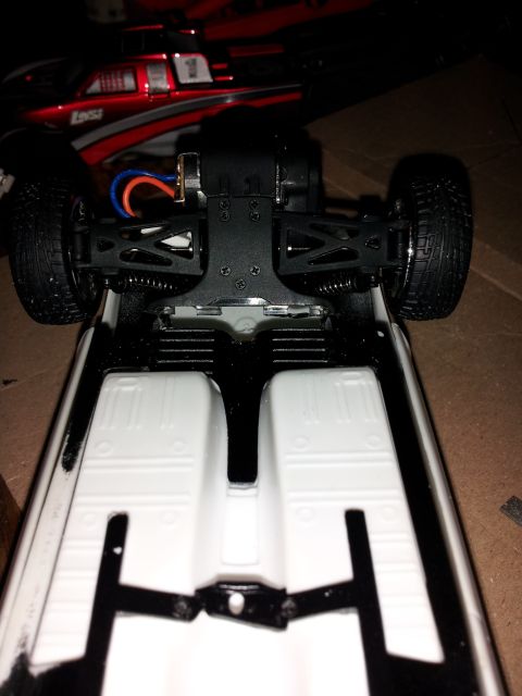 1995 Ford Bronco - The underside of a remote control car chassis is shown, with another RC car in the background.
