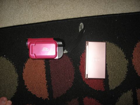 1994 Ford Bronco - A pink camcorder and a rose gold Nintendo DS are placed on a rug with a circular pattern.