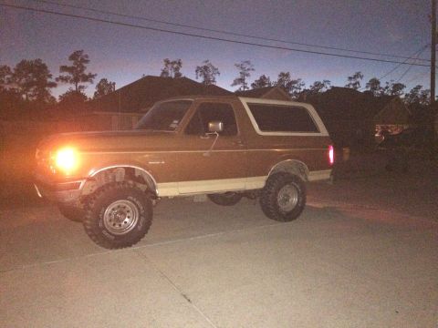 1991 Ford Bronco - This lifted Ford Bronco, likely from the late 1980s, is shown from the side under a twilight sky.