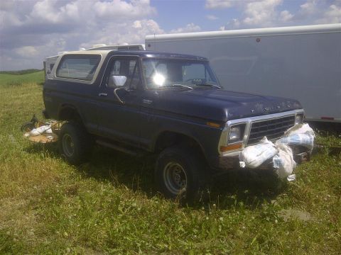 1979 Ford Bronco - This 1978 Ford Bronco is parked in a grassy field next to a trailer.
