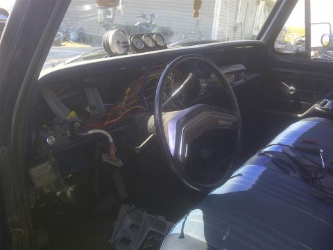 1979 Ford Bronco - The interior of a 1979 Ford Bronco shows a disassembled dashboard with exposed wires and aftermarket gauges.