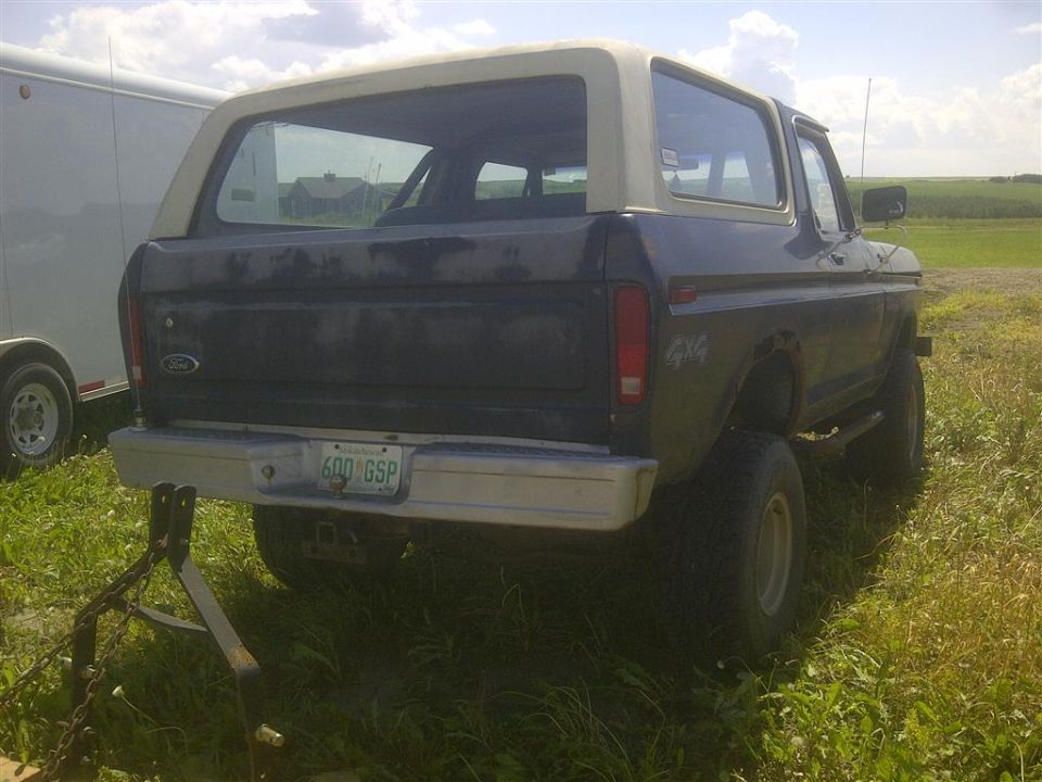 1978 Ford Bronco rear view, parked in grassy field next to a trailer