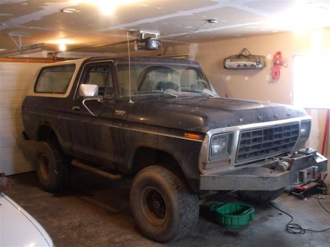 1979 Ford Bronco - This 1979 Ford Bronco is parked in a garage, showing its distinctive body style and dark paint with a white top.